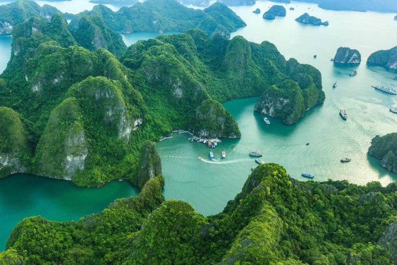 A breathtaking view of Ha Long Bay, Vietnam, with lush green islands and boats cruising through the emerald waters.