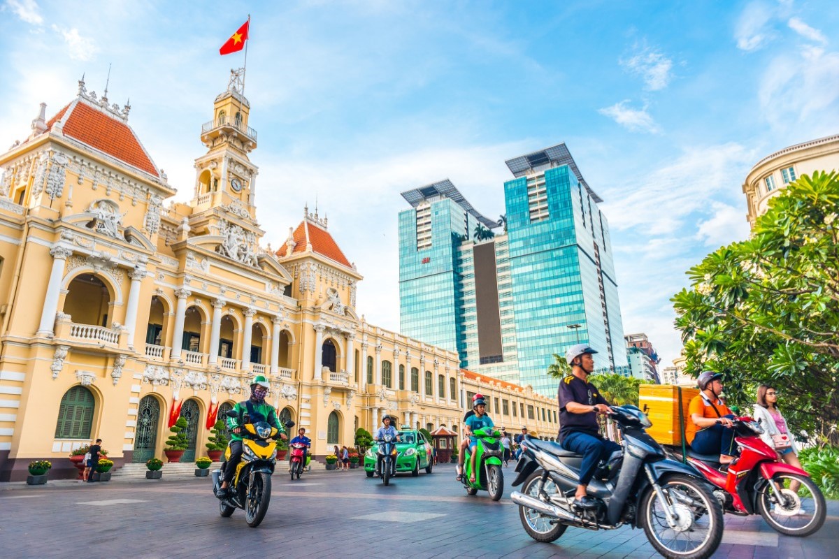 Ho Chi Minh City People's Committee Building with motorbikes passing by, representing the iconic French colonial architecture.