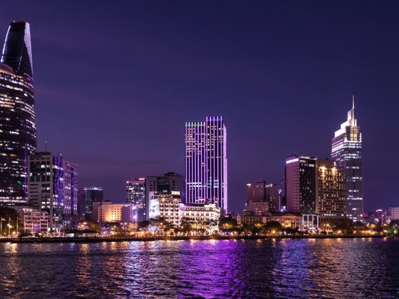 Ho Chi Minh City skyline illuminated at night with skyscrapers reflecting over the Saigon River.