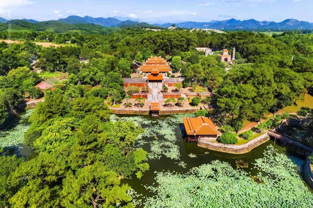 A scenic view of Hue city tour by boat along the Perfume River with lush greenery surrounding the water.