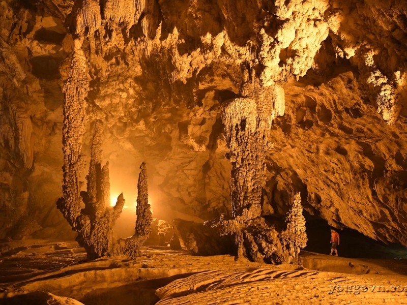 An adventurer exploring the depths of Nguom Ngao Cave in Cao Bang, surrounded by limestone formations.