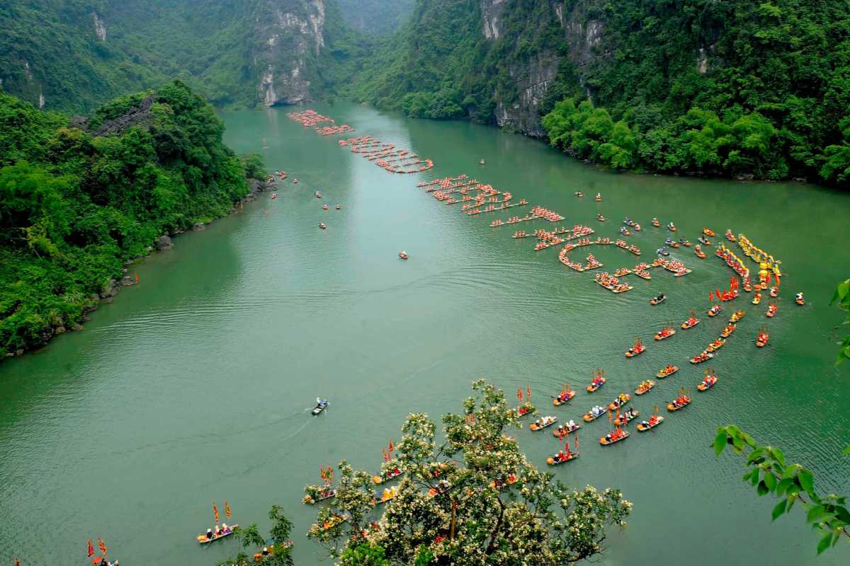 Ninh Binh Vietnam Colorful Boat Festival on River Traditional boat festival in Ninh Binh Vietnam features colorful boats decorated with flags on a calm river.