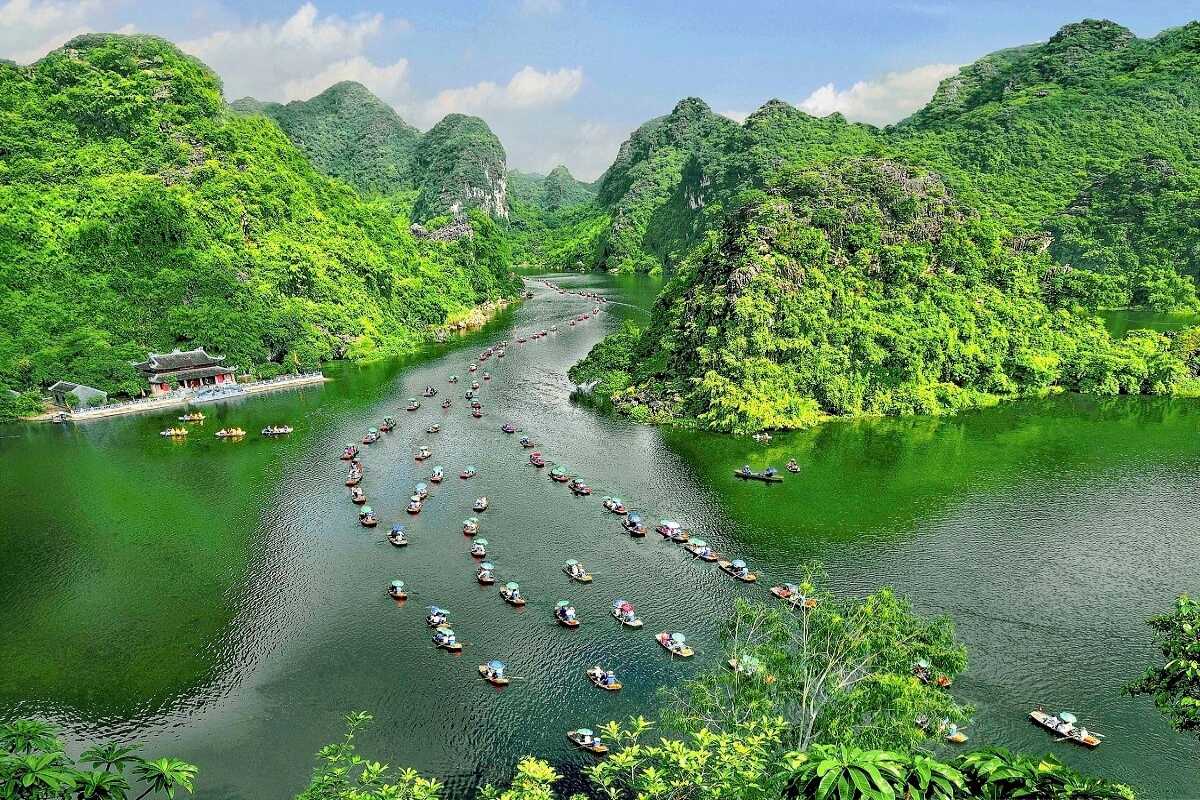 Ninh Binh Vietnam River Cruise Through Lush Limestone Mountains Scenic boat tours in Ninh Binh Vietnam pass through lush green limestone mountains and calm winding rivers.