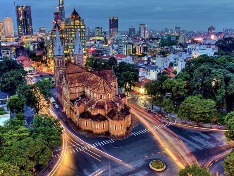 Aerial view of Notre Dame Cathedral Basilica of Saigon at twilight, showcasing its Romanesque design amid the modern cityscape.