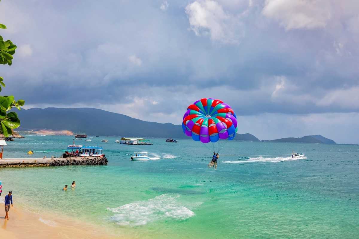 Water Sports at Nha Trang Beach Parasailing adventure at Nha Trang Beach with clear skies and turquoise sea in the background.