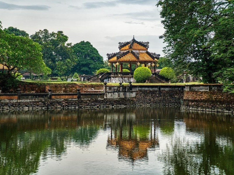 A tranquil view of the Hue Imperial City surrounded by water and greenery, showcasing its architectural beauty.