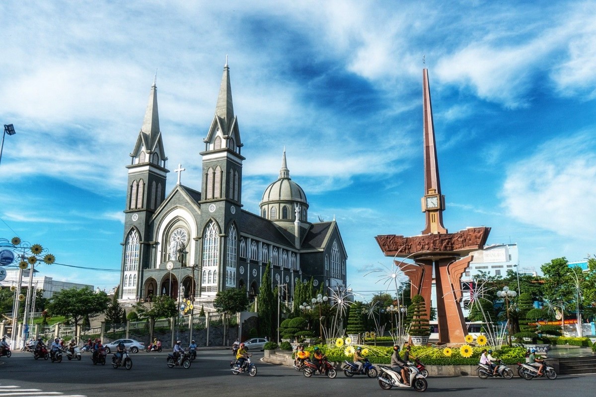 Phu Cuong Cathedral in Binh Duong with motorcycles passing by in traffic.