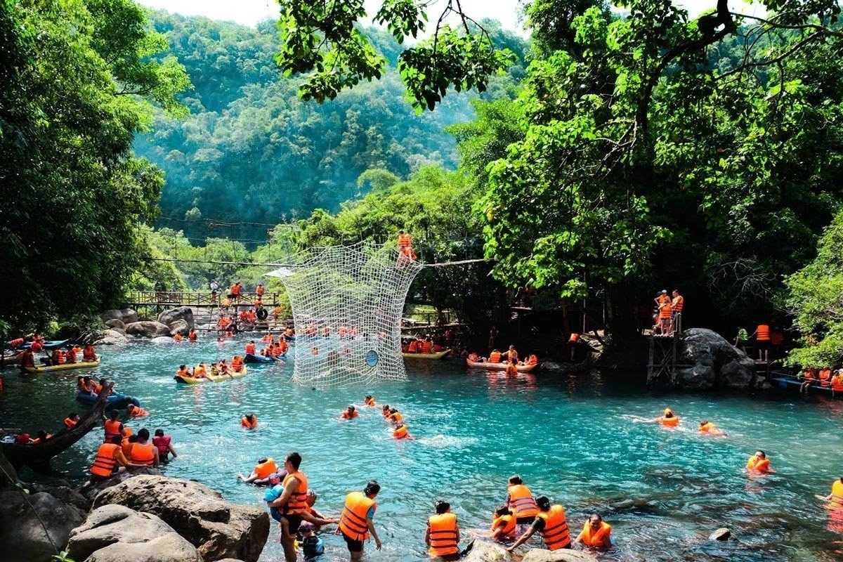 Quang Binh Travel Guide Vietnam Mooc Spring River Activities Quang Binh Travel Guide Vietnam showing tourists kayaking and swimming in the clear waters of Mooc Spring surrounded by lush jungle