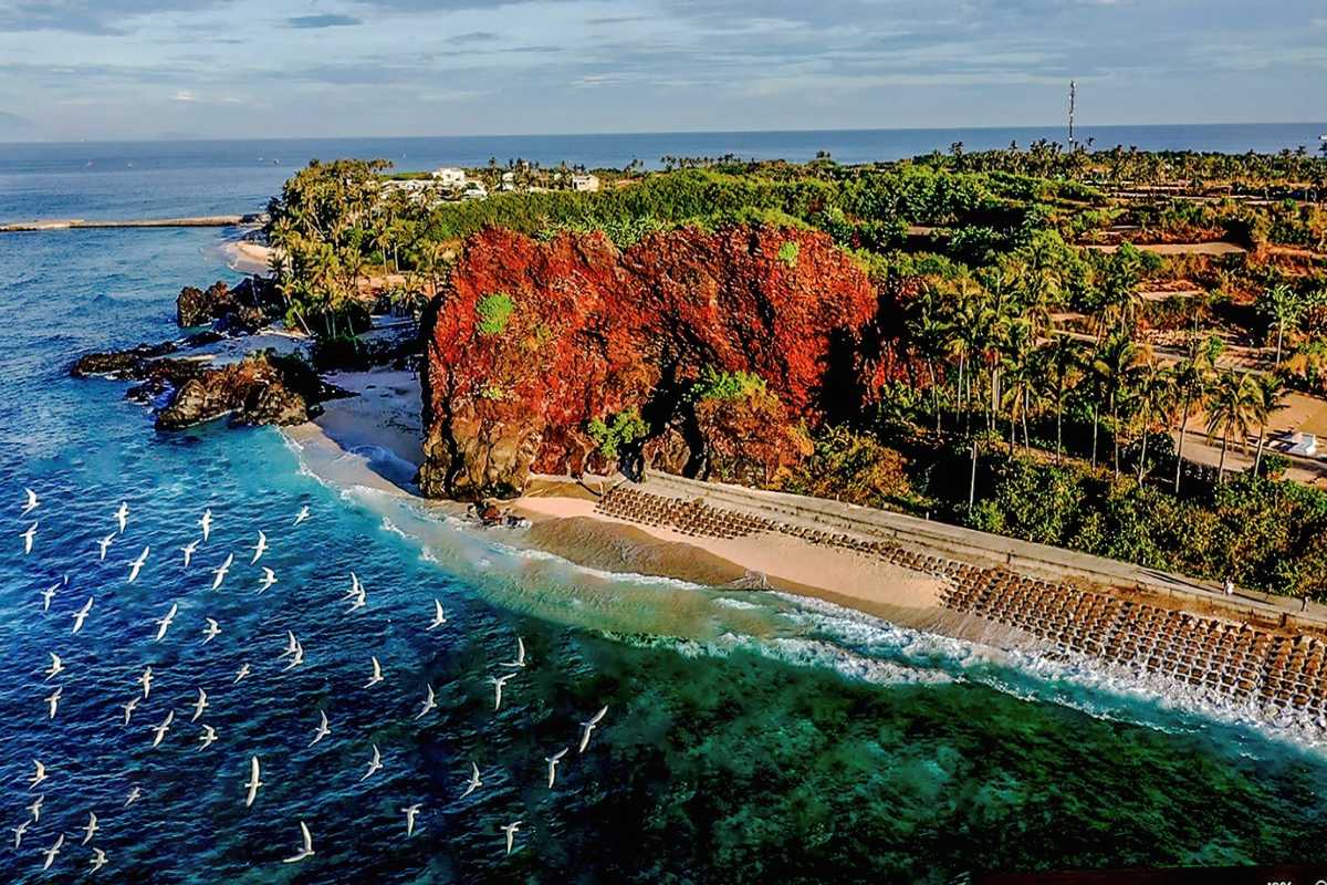 Quang Ngai Red Cliff Beach and Turquoise Waters Vibrant red cliff overlooking turquoise waters and sandy beach in Quang Ngai, Vietnam.