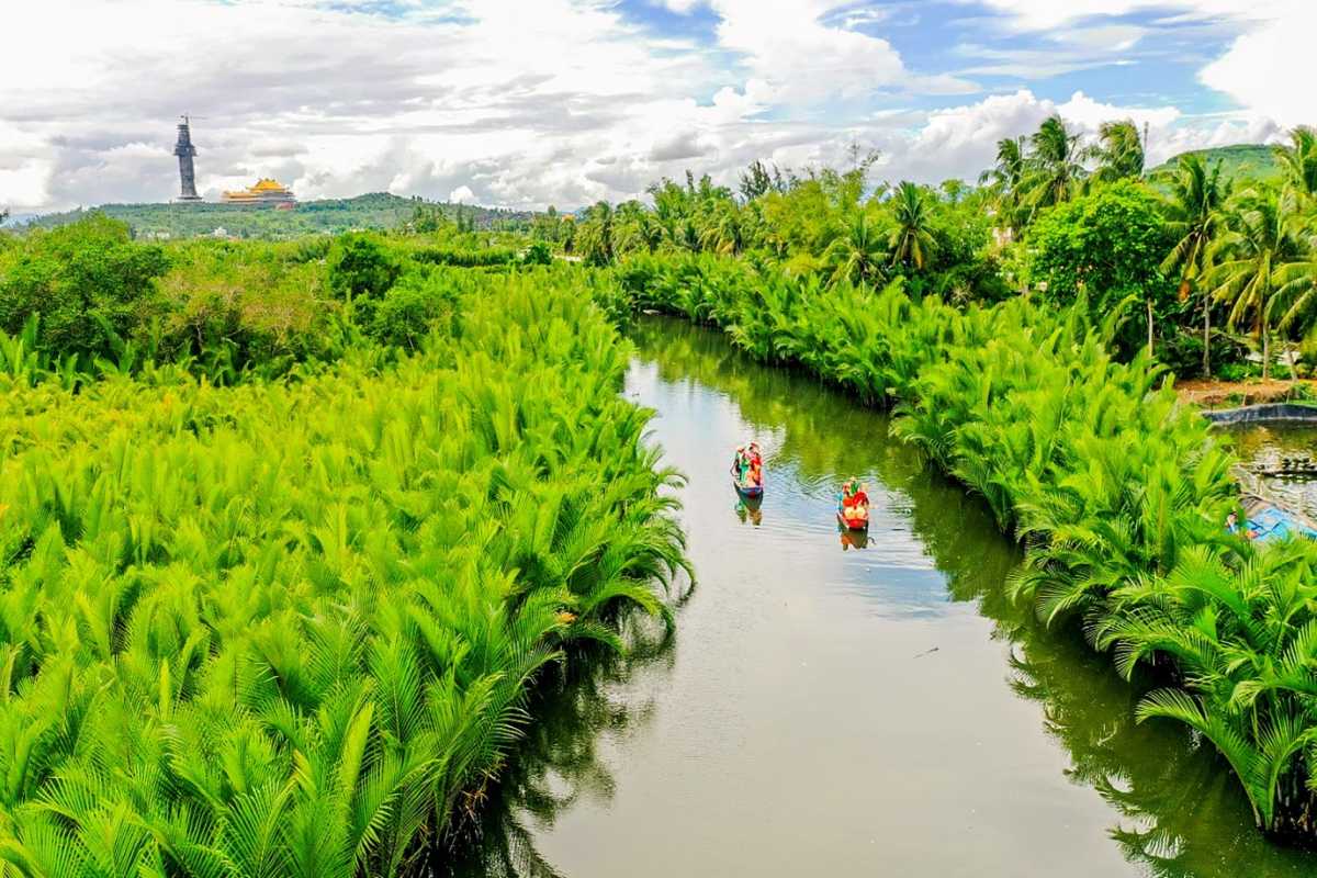 Quang Ngai River and Palm Tree Landscape Scenic river flanked by dense palm trees with mountains in the background in Quang Ngai, Vietnam.