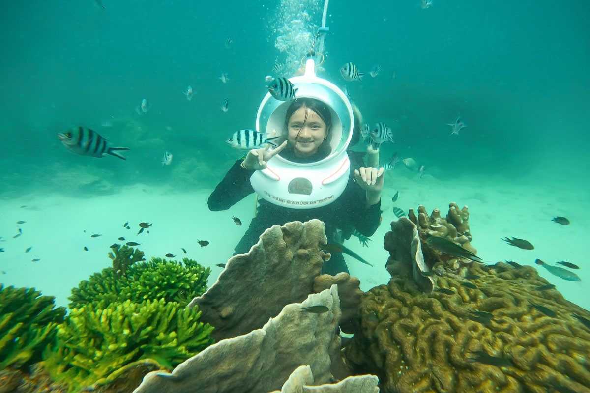 Sea Walking in Nha Trang Bay A traveler enjoys sea walking in Nha Trang Bay surrounded by colorful coral and striped fish.