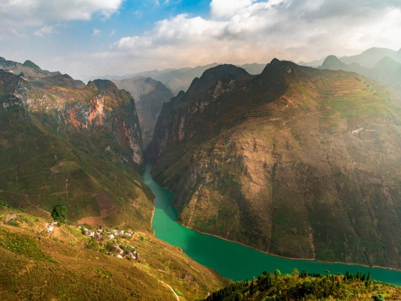 Serene and scenic view of Ma Pi Leng Pass in Ha Giang, Vietnam, with winding roads and towering mountains.