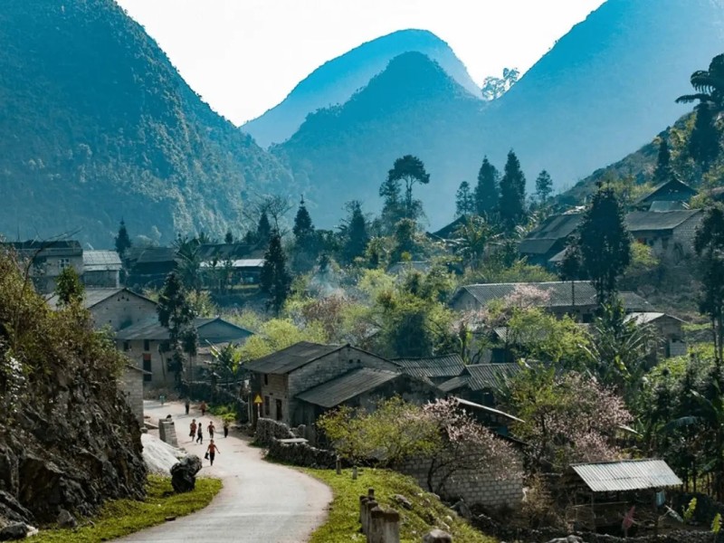 The scenic Sung La Valley in Ha Giang, Vietnam, with green fields and traditional houses surrounded by mountains.