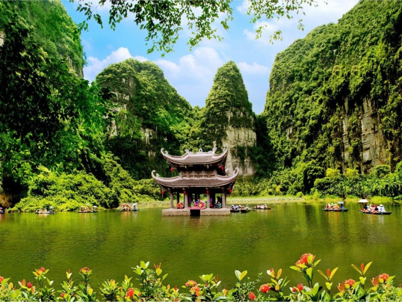 Breathtaking view of Tam Coc river in Ninh Binh, surrounded by lush greenery and limestone mountains.