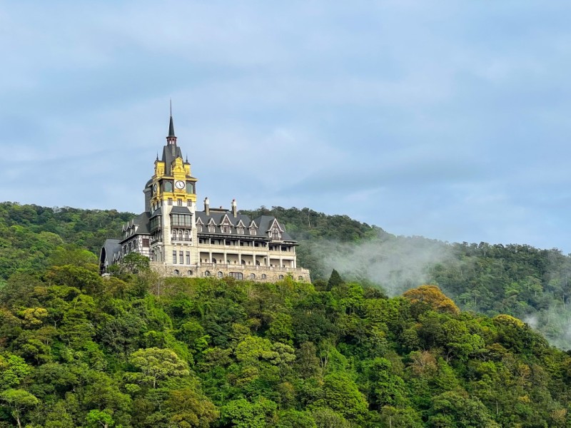 A majestic castle with gothic architecture sitting on a green hillside in Tam Dao.