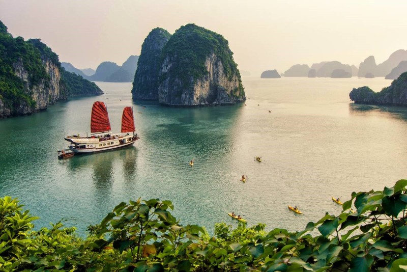 A traditional junk boat cruising through Ha Long Bay, showcasing the iconic limestone islands and serene waters.