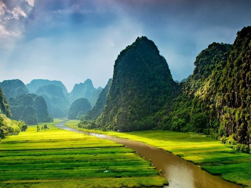 Scenic view of Trang An river system in Ninh Binh, with limestone cliffs and lush greenery.