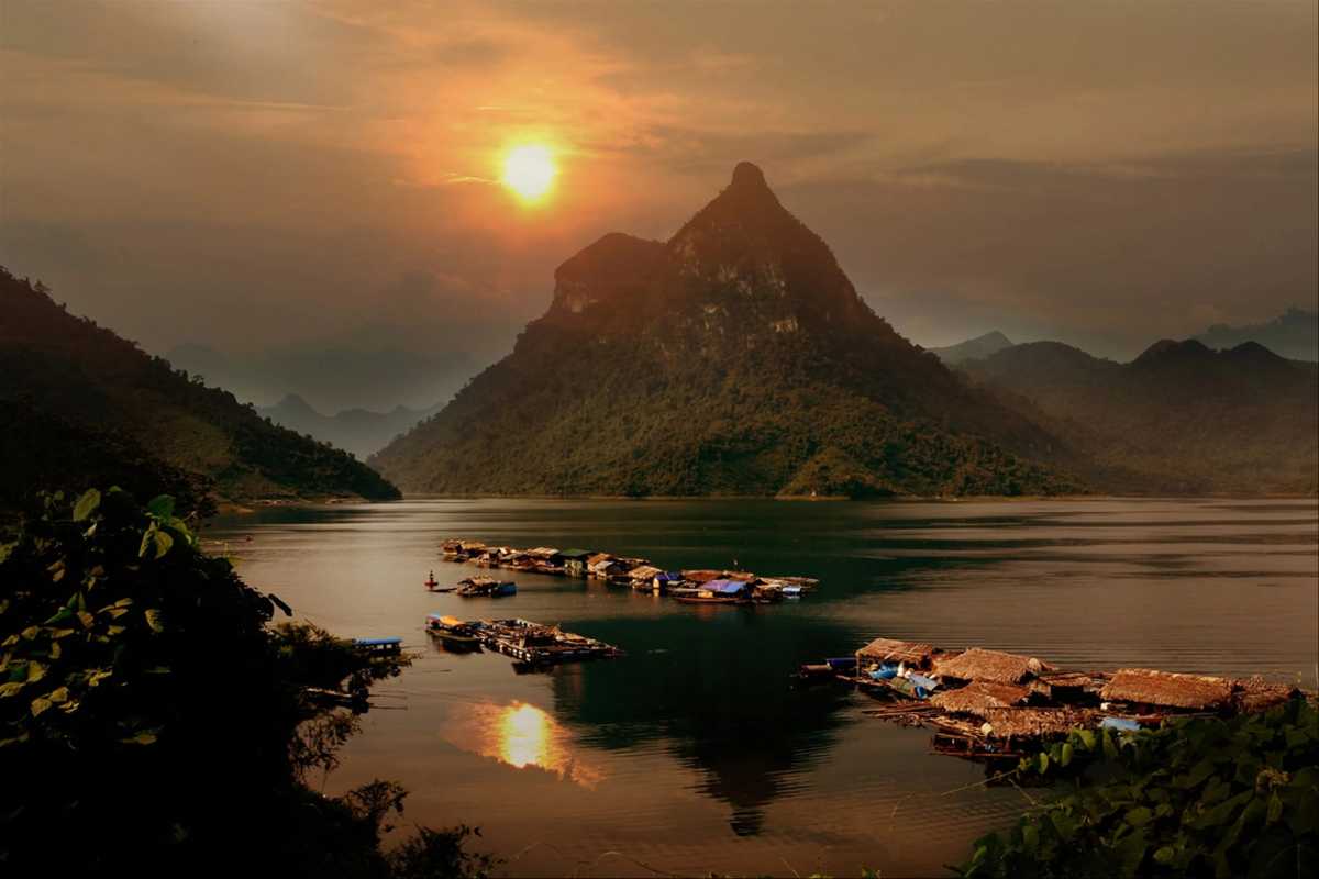 Tuyen Quang Mountain Lake with Boat on Calm Water Small boat gliding on calm lake waters with dramatic mountain scenery in Tuyen Quang