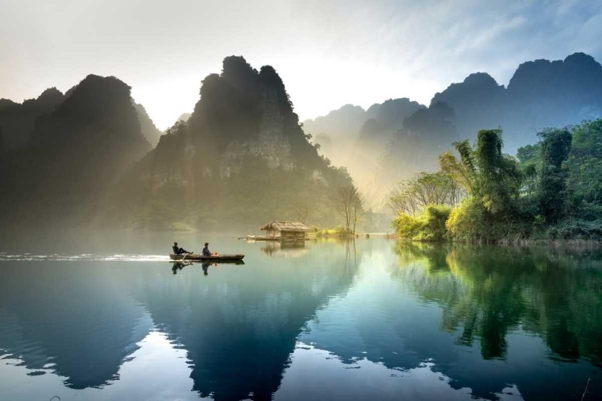 Tuyen Quang River Boat Journey Through Forested Mountains Small boat navigating the calm river bordered by dense green mountains in Tuyen Quang