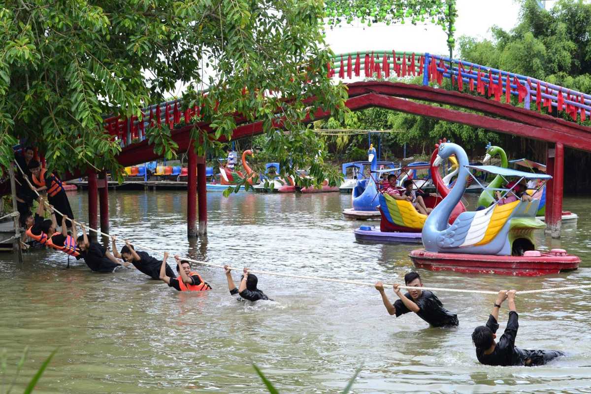 Vinh Long family recreation park with water fun Vinh Long family recreation park featuring colorful paddle boats and children enjoying water activities under lush trees