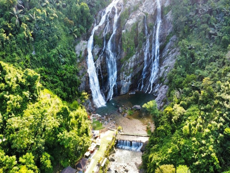 Stunning view of White Waterfall Minh Long in Quang Ngai cascading over lush green forests.