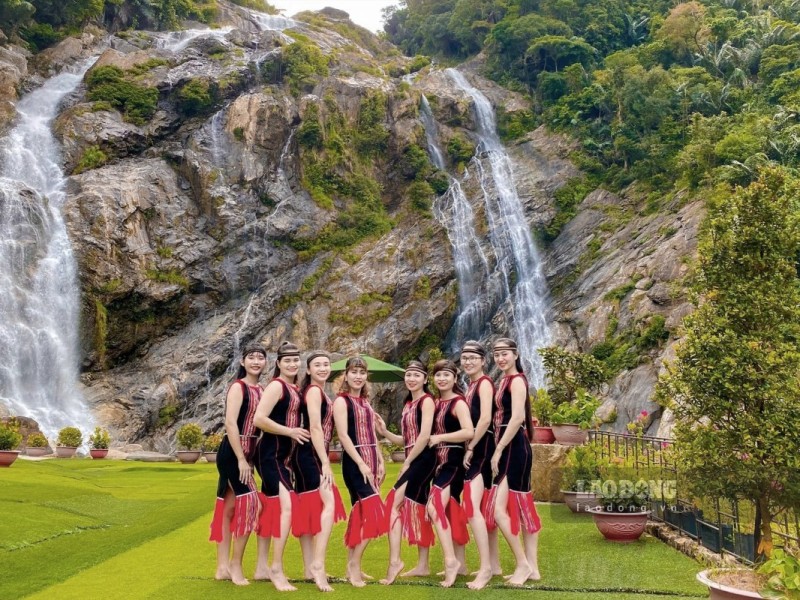 Group of tourists enjoying White Waterfall Minh Long Quang Ngai with scenic surroundings.