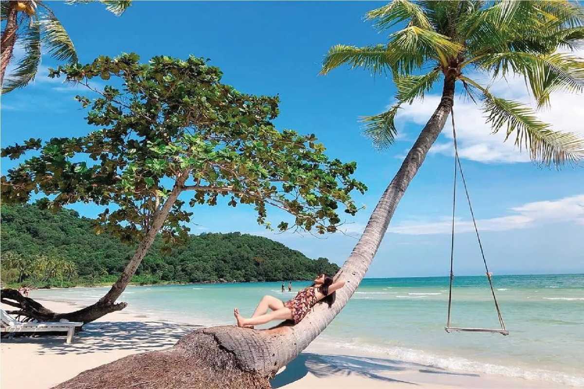 Visitor lying on a leaning palm tree along the shore of May Rut Island during the 4 Islands Trip By Speed Boat to Xuong Island – Buom Island – Gam Ghi Island – May Rut Trong Island
