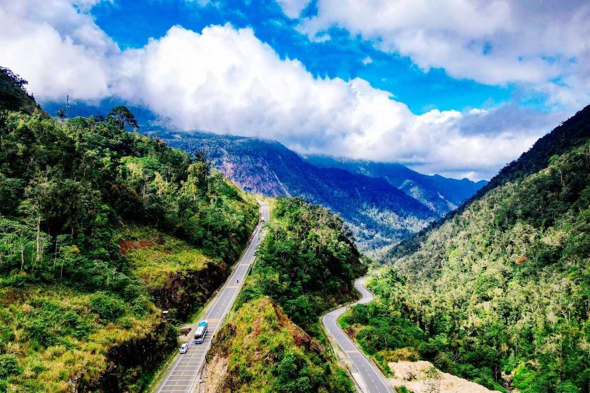Mountain road curving through lush valleys with distant peaks on the Nha Trang biking and rafting tour.