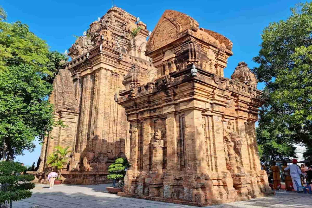 Diagonal view of Ponagar Temple's preserved Cham architecture with blue sky and trees in background