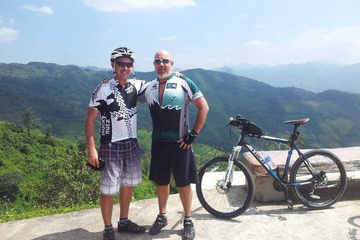 Two cyclists posing with their bikes at a scenic mountain viewpoint along the Nha Trang cycling route.