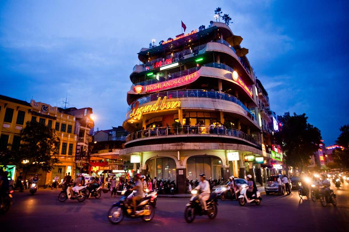Motorbikes weaving through Hanoi streets at dusk during the Hanoi motorbike tour