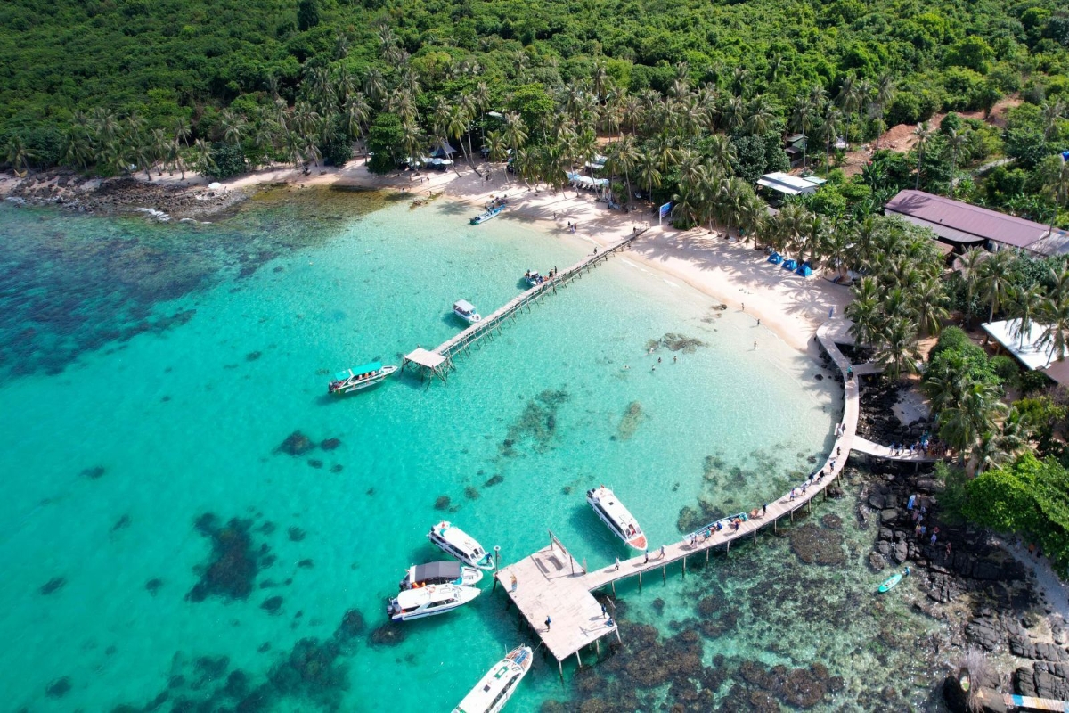 Boats moored at the wooden pier of May Rut Island, offering access to white sand beaches and palm shade.