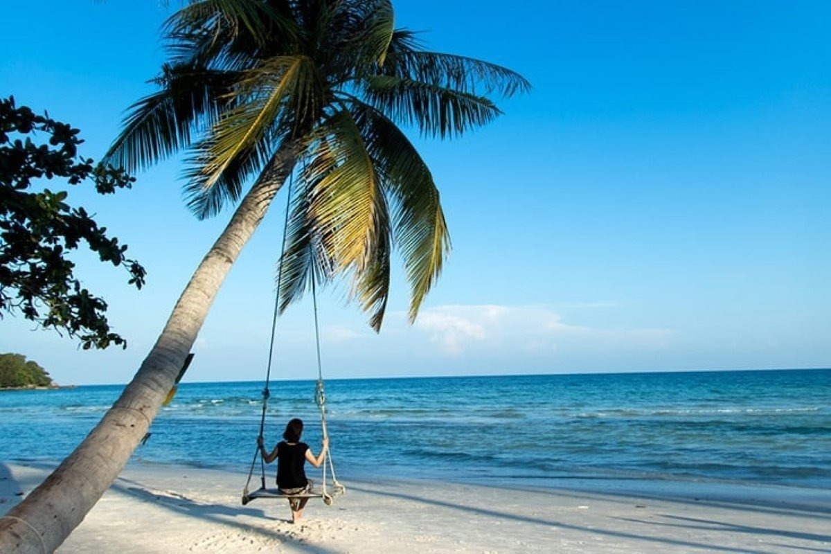 Traveler swinging on a beachside palm tree with the sea in the background in Phu Quoc