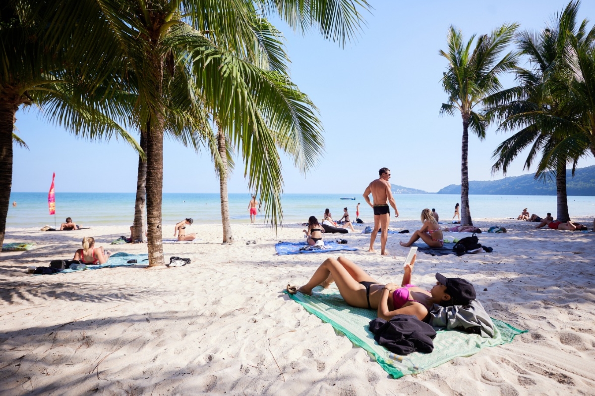 Tourists sunbathing and relaxing on a palm-lined beach with white sand in Phu Quoc