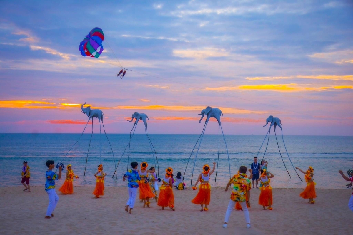 Tourists watching beach performers and dancers during a colorful sunset at Sunset Sanato