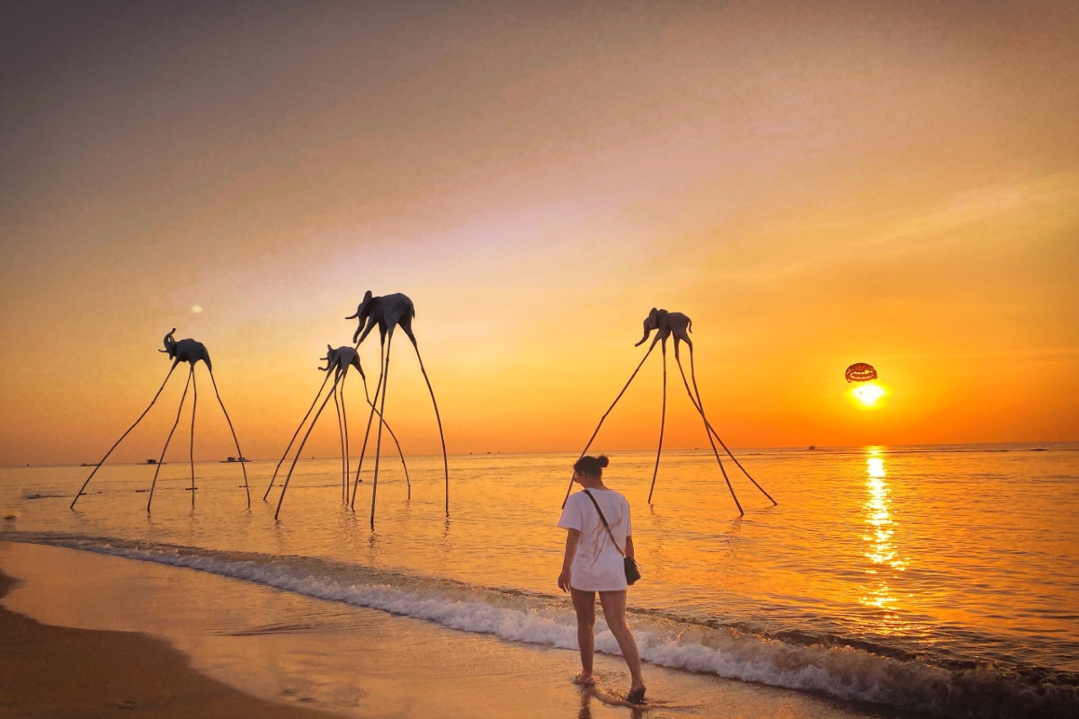 Traveler walking by the sea at Sunset Sanato with elephant sculptures at sunset in Phu Quoc