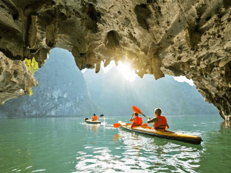 Tourists kayaking through Luon Cave in Halong Bay, illuminated by natural light