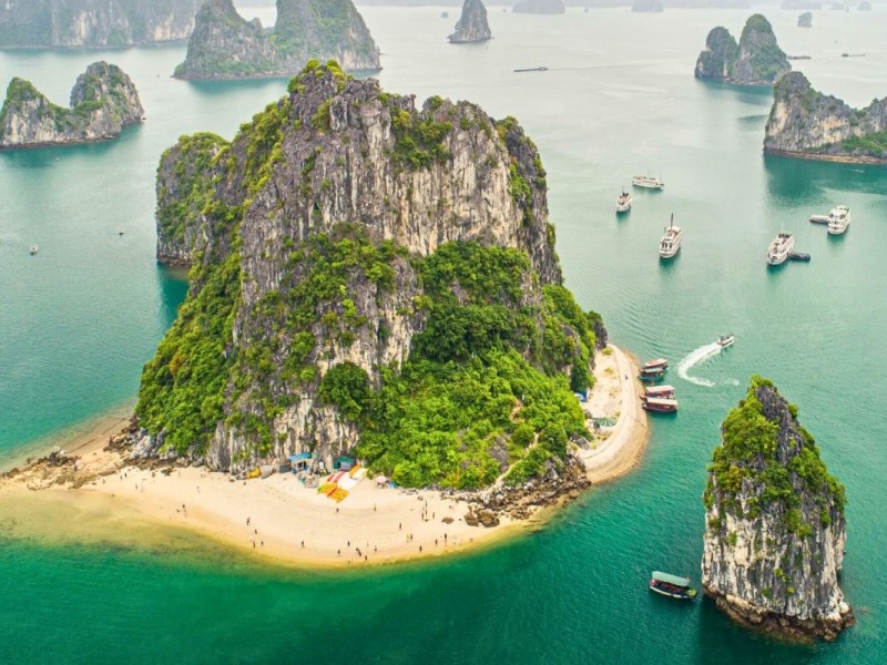 Beachgoers enjoying the water at Titov Island, Halong Bay, with lush greenery in the background